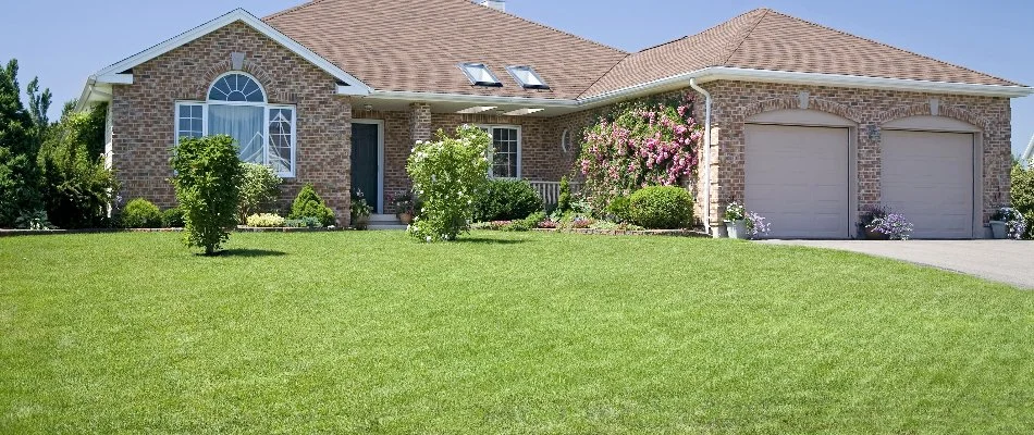 Brick house in Overland Park, KS, with a green lawn and flowering shrubs.