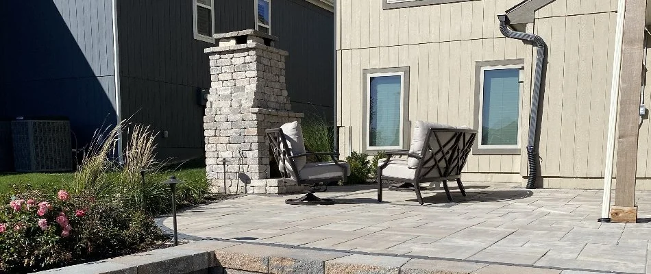 Patio in Mission, KS, with outdoor fireplace and chairs.