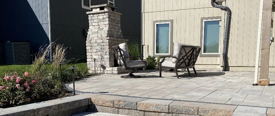 Paver patio in Overland Park, KS, with chairs and an outdoor fireplace.