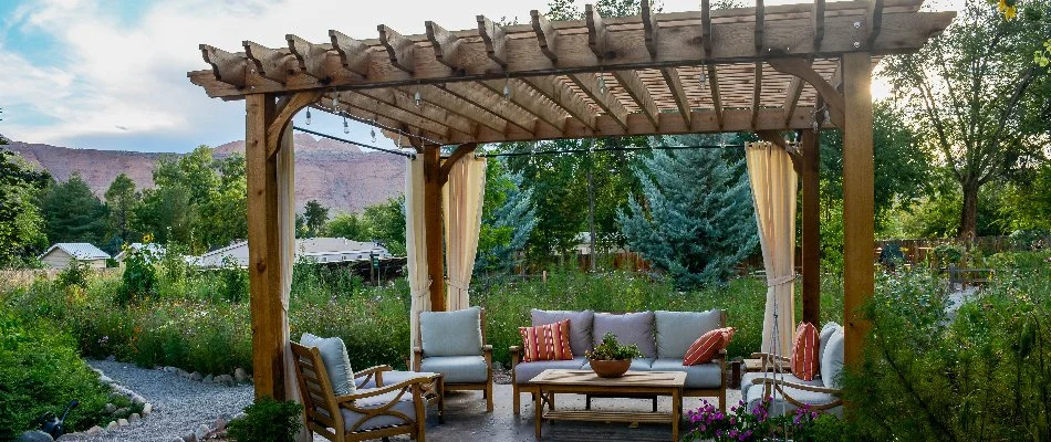 Wooden pergola with furniture under it.